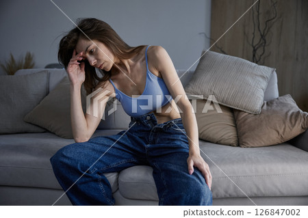 Upset woman feeling not perfect enough touching her head sitting on the sofa 126847002