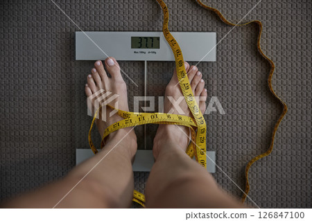 Unrecognizable woman standing on floor scales displaying low weight 126847100