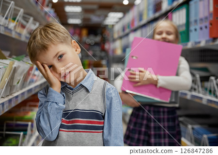 Frustrated boy feeling tired and irritated during shopping at stationery store Frustrated boy feeling tired and irritated during shopping at stationery store 126847286