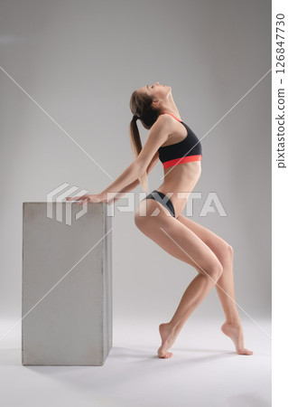Woman in a sporty pose showcasing athleticism in a studio setting 126847730