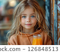 Portrait of smiling child drinking an orange juice close up 126848513
