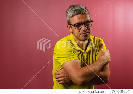 Man in yellow shirt demonstrates discomfort in studio setting 126848695