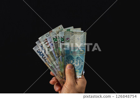 Hand holding various banknotes with a dark background 126848754