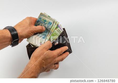 Hands holding currency while opening a black wallet 126848780