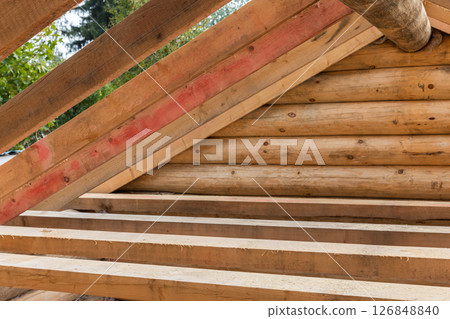 Detailed view of a wooden roof structure showing angled beams and logs 126848840