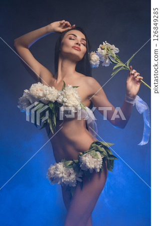 Brunette woman gracefully poses with flowers in an artistic setting 126849285
