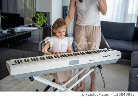 Individual piano lesson for a young child at home in the living room. Concept of early childhood development through personalized music education. 126849932