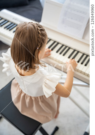 Little girl playing piano at home in the living room. Childhood creativity and musical development in cozy family environment 126849960