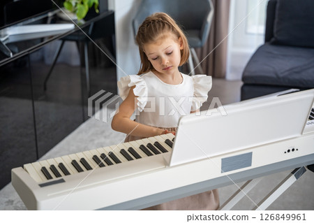 Little girl playing piano at home in the living room. Childhood creativity and musical development in cozy family environment 126849961