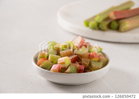 Freshly chopped green rhubarb in white bowl on white background. Trendy organic food. Ready for cooking. Vegan concept. Close up. 126850472