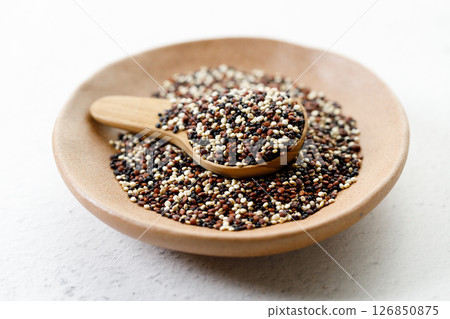 Mix of white, black and red quinoa seeds in wooden spoon. 126850875