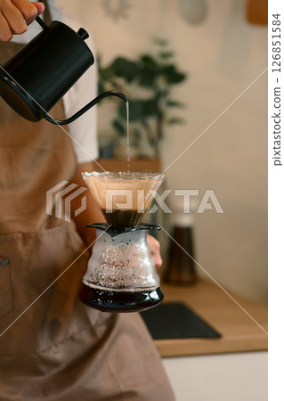 Man wearing an apron preparing fresh pour over coffee in a cozy kitchen Man wearing an apron preparing fresh pour over coffee in a cozy kitchen 126851584