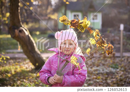 Young Girl Holding Rake with Autumn Leaves in Garden Young Girl Holding Rake with Autumn Leaves in Garden 126852613