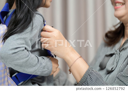 Morning Routine. Mother helping daughter with her backpack at home. 126852792