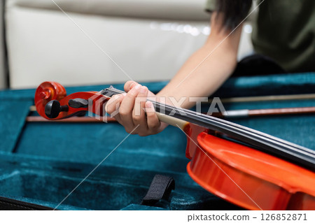 Music Instruments and Learning. A close-up of a child's hand holding a violin in a case. 126852871
