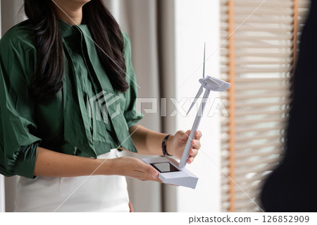 ESG Focus on Renewable Energy. Woman presenting wind turbine model in a corporate setting. 126852909