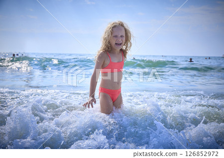 Child Joyfully Playing in Shallow Ocean Waves at the Beach 126852972