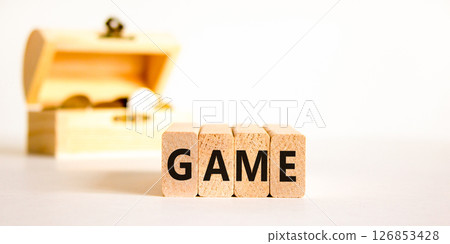 Game symbol. Concept word Game on beautiful wooden blocks. Beautiful wooden chest with coins. Beautiful white table white background. Business, lifestyle and game concept. Copy space. Game symbol. Concept word Game on beautiful wooden blocks. Beautiful wooden chest with coins. Beautiful white table white background. Business, lifestyle and game concept. Copy space. 126853428