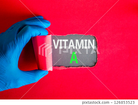 Vitamin A symbol. Concept words Vitamin A on beautiful grey paper. Doctor hand in blue medical glove. Beautiful red background. Medical healthy lifestyle Vitamin A concept. 126853523