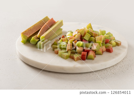 Freshly chopped green rhubarb on white chopping board on white table top. Trendy organic food. Ready for cooking. Vegan concept. Close up. 126854011