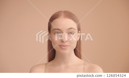 Portrait of a confident young Caucasian lady looking a camera on Isolated Peach background. Portrait of a confident young Caucasian lady looking a camera on Isolated Peach background. 126854324