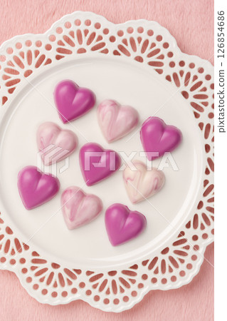 Aerial view of heart-shaped chocolates on a plate against a pink background 126854686