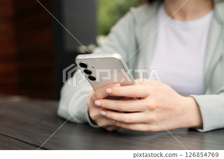 Close-up of hands holding and using a modern smartphone outdoors, showcasing technology and connectivity in daily life 126854769