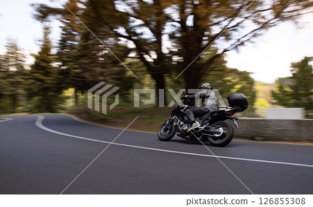Driver riding motorcycle on empty asphalt road, spring mountains Driver riding motorcycle on empty asphalt road, spring mountains 126855308