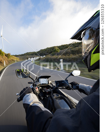 Driver riding motorcycle on empty asphalt road, handlebars view , spring mountains Driver riding motorcycle on empty asphalt road, handlebars view , spring mountains 126855310