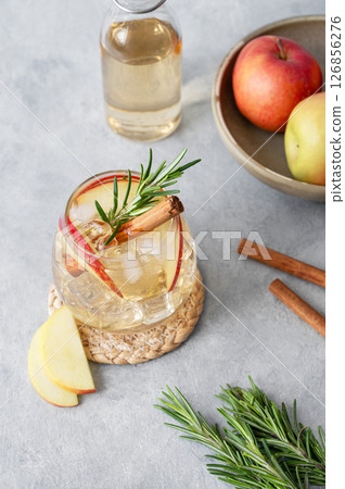 Apple cocktail or cider with ice, garnished with cinnamon and rosemary in a glass Apple cocktail or cider with ice, garnished with cinnamon and rosemary in a glass 126856276