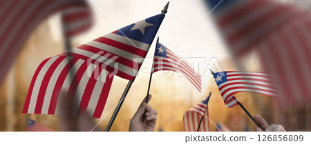 Liberia flags in their hands on a blurred urban background 126856809