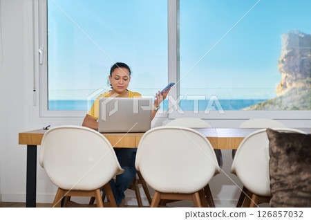 Confident Freelancer Working Remotely in a Scenic Home Office Setting Confident Freelancer Working Remotely in a Scenic Home Office Setting 126857032