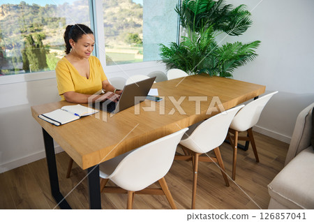 Female Freelancer Working Online in a Bright Modern Home Office with Wooden Decor 126857041