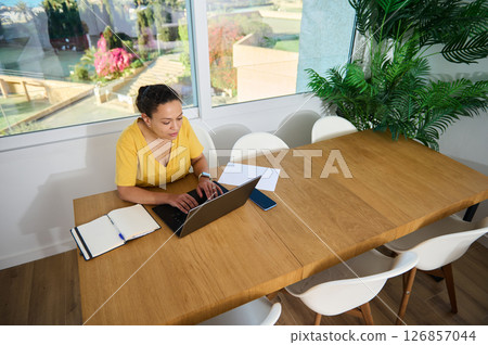 Focused Woman Working on Laptop at Home Office with Bright Comfortable Decor 126857044