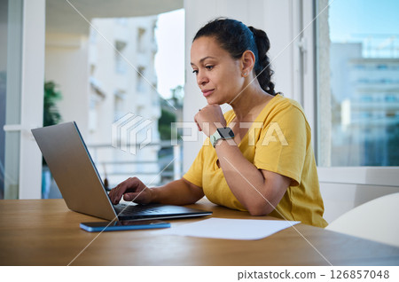 Focused Professional Woman Working Remotely From Home on Laptop 126857048