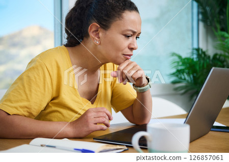 Focused Woman Working on a Laptop in a Bright Home Office Setting 126857061