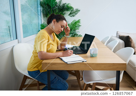 Focused Woman Working on a Project in a Home Office Setting Focused Woman Working on a Project in a Home Office Setting 126857067