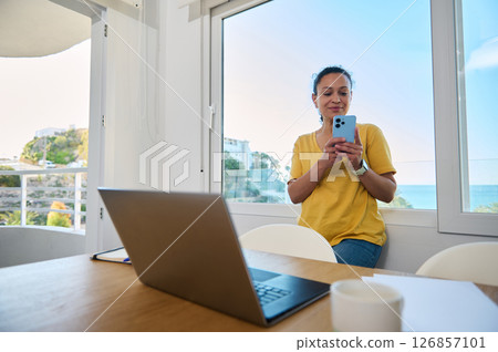 Confident Businesswoman Using Smartphone in Bright Office with Scenic Window View 126857101