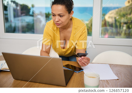 Woman Working on Laptop at Home Engaged in Online Tasks and Shopping 126857120