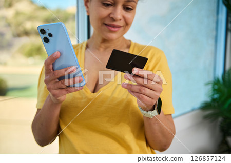 Woman Holding Smartphone and Card in Bright Interior 126857124