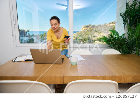 Woman Working Remotely in a Bright Home Office With Scenic View Woman Working Remotely in a Bright Home Office With Scenic View 126857127