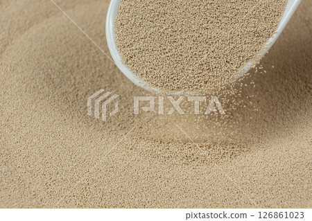 Dry yeast is poured out of a spoon Dry yeast is poured out of a spoon 126861023