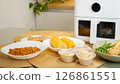 Air fryer cooking various dishes including corn, muffins, and vegetables 126861551