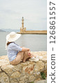 Tourist admiring chania lighthouse from venetian harbor wall in crete 126861557