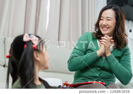 Music Education and Joyful Learning. A mother smiling and engaging with her daughter during a music lesson. 126861656