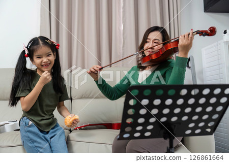 Learning Violin Together. Mother and daughter enjoying music at home. 126861664