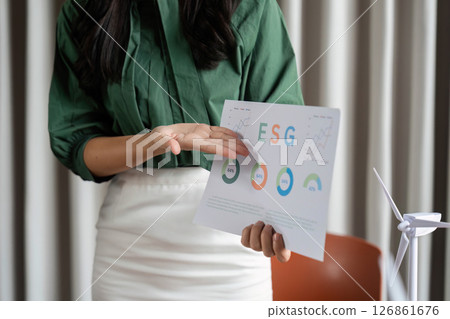 ESG Data Analysis. Businesswoman showcasing sustainability charts in a meeting. ESG Data Analysis. Businesswoman showcasing sustainability charts in a meeting. 126861676