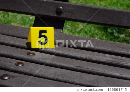 One yellow crime scene marker on a wooden bench 126861745