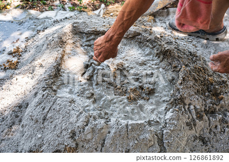 Manual concrete mixing with sand, cement and water, using shovel and trowel on outdoors Manual concrete mixing with sand, cement and water, using shovel and trowel on outdoors 126861892
