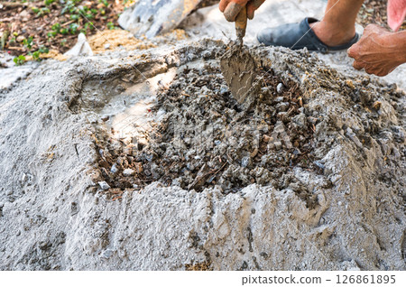 Manual concrete mixing with sand, cement and water, using shovel and trowel on outdoors 126861895